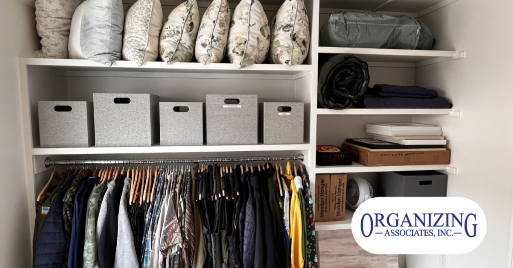 A custom residential closet system organized with gray storage bins neatly folded pillows and hanging clothes.